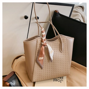 Dettaglio della borsa tote intrecciata con un foulard decorativo in seta sul manico