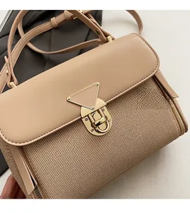 Close-up of contrast crossbody bag with woven texture and gold triangle lock detail