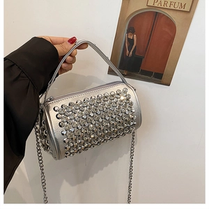 Detail of a silver rhinestone cylinder bag with a metallic chain strap and handle