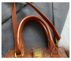 Detail of brown crocodile pattern handbag showing reinforced handles and gold hardware