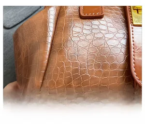 Detail shot of brown crocodile texture leather and golden square metal lock on handbag