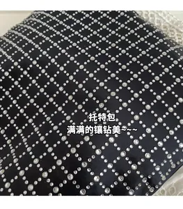 Makro-Detail des glänzenden Strass-Gittermusters auf schwarzer Satin-Schultertasche