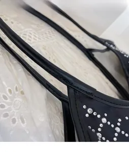 Detail eines schwarzen Leder-Schulterriemens mit glitzernden Strasssteinen auf Stoff