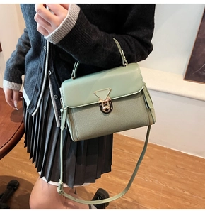 Detail of sage green handbag with golden triangle lock and textured fabric finish
