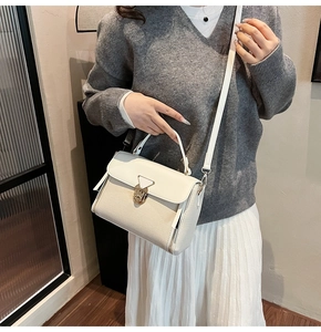 Detail of cream crossbody bag featuring mixed textures and golden clasp on a model