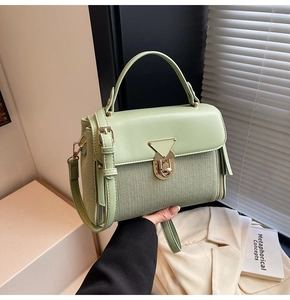 Detail of light green woven handbag with golden triangle clasp and smooth leather handle