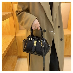 Detail of black crocodile pattern Boston bag with gold twist lock and dual handles