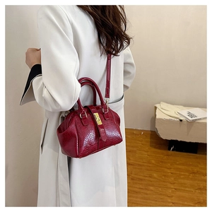 Detail of red crocodile pattern handbag with golden buckle and adjustable strap