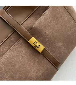 Close-up of brown tote bag showing smooth leather and suede texture with gold metal buckle