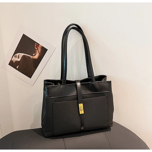 Detail of classic black leather tote bag featuring a polished metal buckle and strap