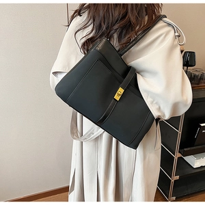 Close-up of a black matte tote bag featuring a metallic gold twist-lock closure detail