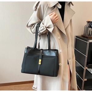 Detail of black tote bag with matte texture, gold metal clasp and premium leather straps