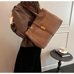 Detail view of brown matte leather tote bag with gold twist lock and strap accents