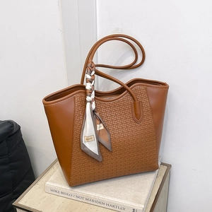 Borsa tote in pelle marrone con trama intrecciata e foulard su tavolo di marmo