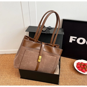 Close-up of brown patchwork tote bag with gold metal clasp in a stylish gift box