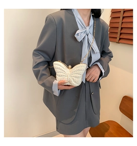 Détail du sac papillon à paillettes avec chaîne dorée sur un blazer gris chic