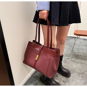 Close-up of burgundy tote bag with matte finish and gold square twist lock detail