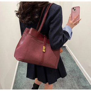 Detail of burgundy tote bag with matte finish, leather patchwork, and golden twist lock