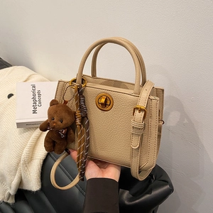 Sac à main beige minimaliste avec texture litchi et breloque ours pour usage quotidien