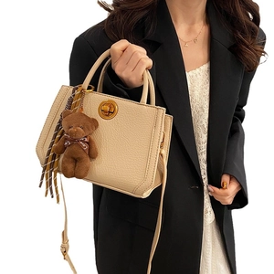 Sac à main beige minimaliste en cuir grainé avec fermoir doré et charme d'ours