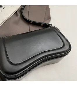 Close-up of black leather shoulder bag with unique wavy edges and gold metal hardware