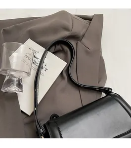 Detail of adjustable slim leather strap and durable metal buckle on a black shoulder bag