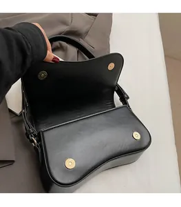 Detail view of the magnetic snap closure and metal buckles on a black matte leather bag