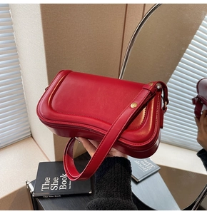 Detailed close-up of a red leather shoulder bag with gold buckle and neat stitching
