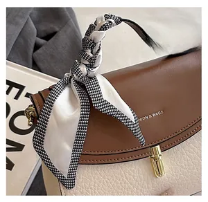 Detail of two-tone crossbody bag featuring a brown leather flap and white lychee texture