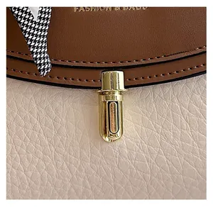 Detail of golden cylinder lock on brown and cream patchwork leather shoulder bag
