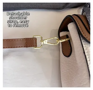 Detail of the detachable shoulder strap with golden metal clasp on a textured leather bag