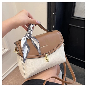 Detail of color-block crossbody bag featuring lychee texture and silk scarf handle decor