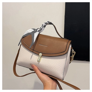 Detail of color-block crossbody bag featuring gold lock and houndstooth scarf handle
