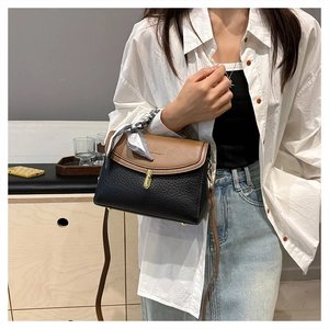 Detail showing two-tone stitching, lychee texture, and polka dot scarf on the shoulder bag