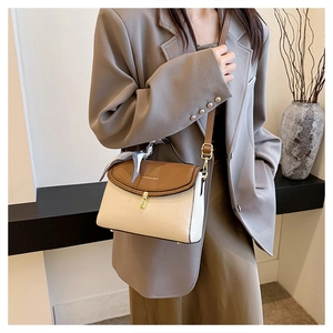 Detail of two-tone crossbody bag with leather texture, scarf handle and golden twist lock