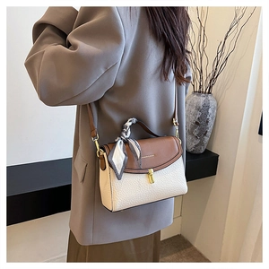 Detail of color-block crossbody bag with silk scarf handle and gold twist lock