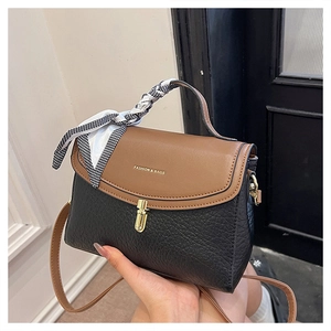 Detail of color-block crossbody bag featuring brown flap, gold clasp and houndstooth scarf