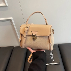 Chic beige crossbody bag with gold triangle lock and top handle shown in lifestyle setting