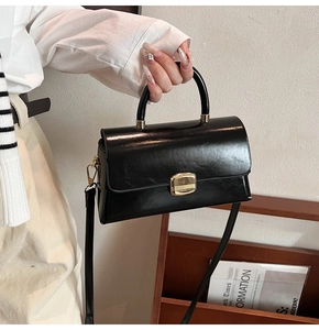 Détail d'un sac à main noir brillant vintage avec boucle carrée dorée et poignée élégante