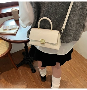 Vue détaillée d'un sac à main blanc crème avec fermoir rotatif rectangulaire doré chic