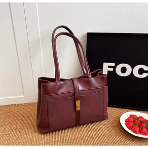 Deep red tote bag with leather suede stitching and golden buckle in a lifestyle setting