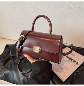 Détail du sac bandoulière bordeaux avec fermoir doré et finition en cuir lisse