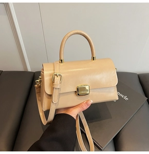Détail du sac à main beige avec texture lisse et élégant fermoir en métal doré brillant