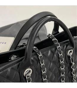 Detailansicht der schwarzen gesteppten Ledertasche mit Tragegriffen und Kette
