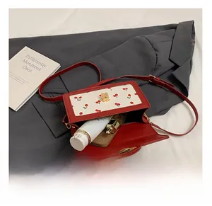 Internal capacity of cherry pattern handbag showing phone, lipstick and essentials