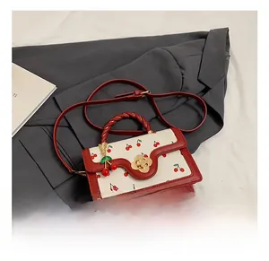 Detail of red leather woven handle and cherry pattern panel with gold flower twist lock
