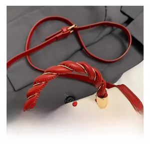 Detail of red cherry print bag with twisted leather handle and gold metal wire spiral