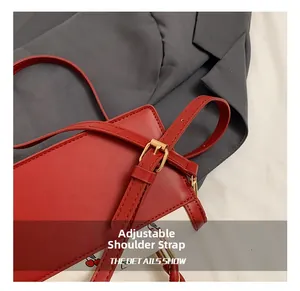 Detail view of the red leather handbag adjustable shoulder strap and gold buckle