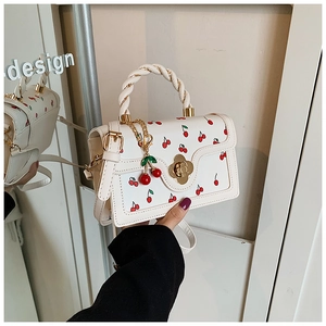 Detailed view of white PU leather square handbag with cherry print and woven handle