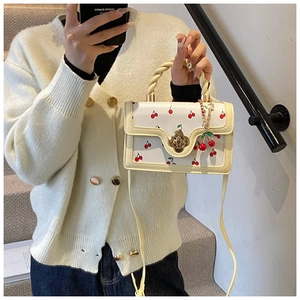 Detail of cream white handbag with red cherry print and golden flower twist lock